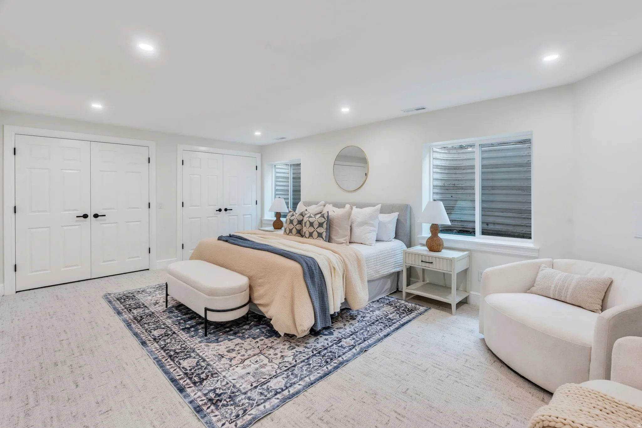 Bedroom featuring light-colored carpeting, two sets of white paneled double doors, recessed ceiling lighting, and two windows
