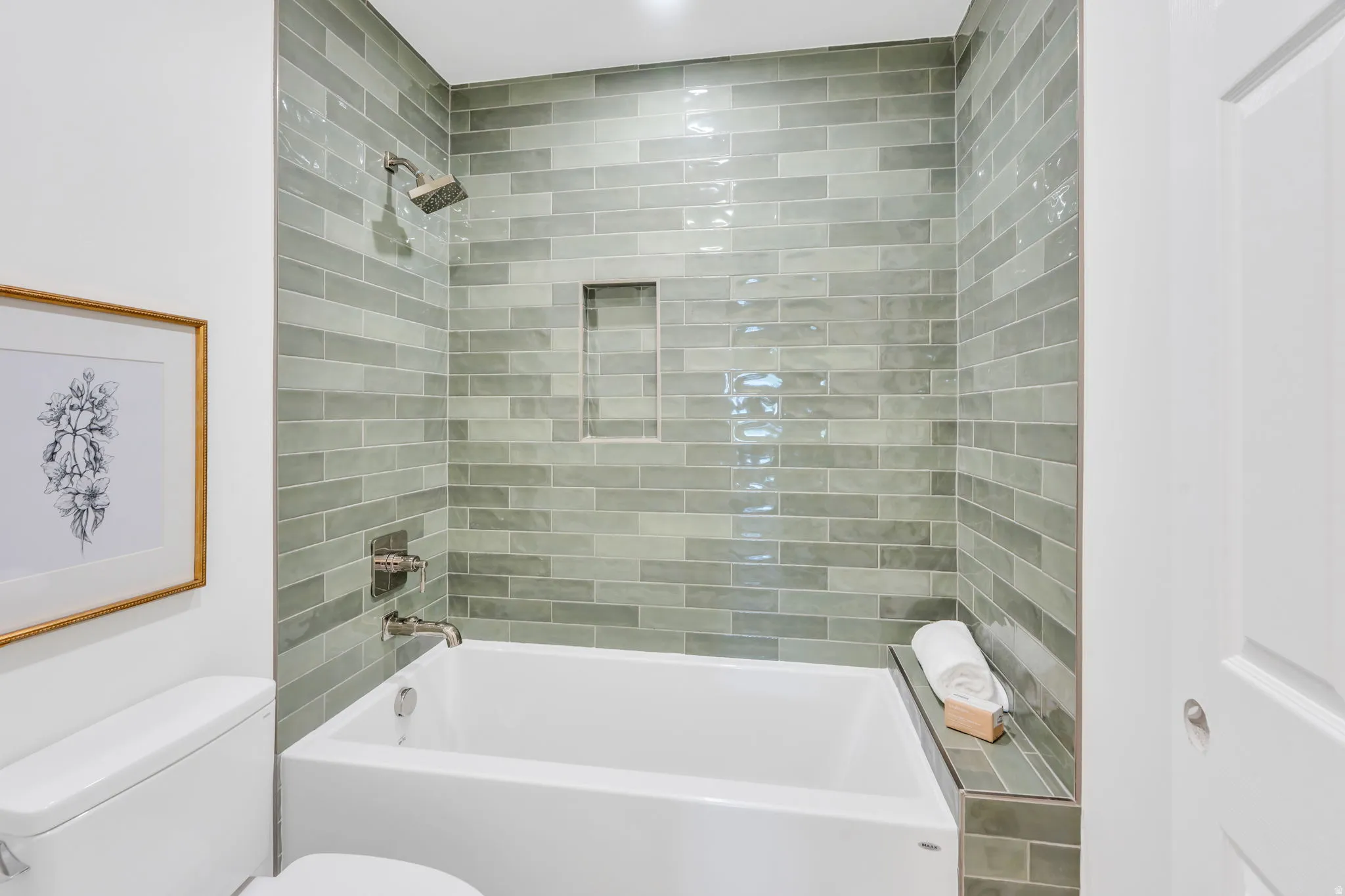 Bathroom with a white tub, subway tile surround, recessed shower niche, and brushed nickel fixtures