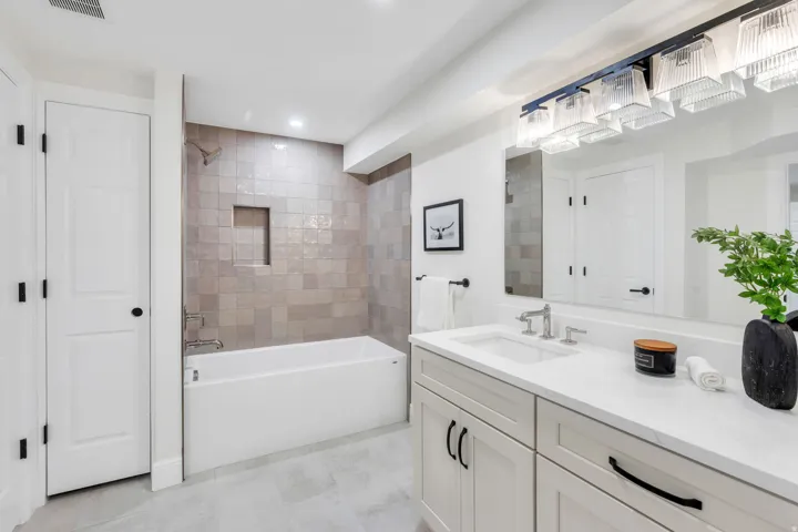 Bathroom featuring a single vanity with stone countertop, undermount sink, and light-colored cabinetry
