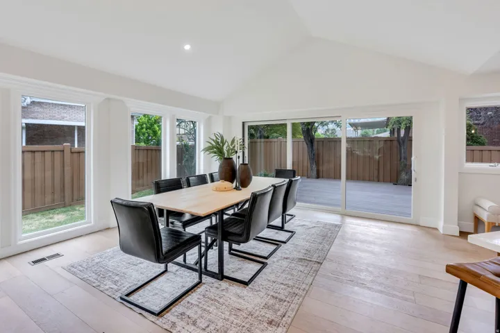 Spacious room featuring a vaulted ceiling with recessed lighting, light wood-finish flooring, and multiple large windows