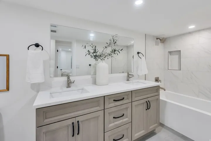 Bathroom featuring a double vanity with light-toned cabinetry, integrated sinks, and a large mirror