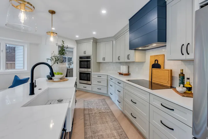 Modern kitchen featuring light cabinetry with black hardware, white countertops, and a subway tile backsplash