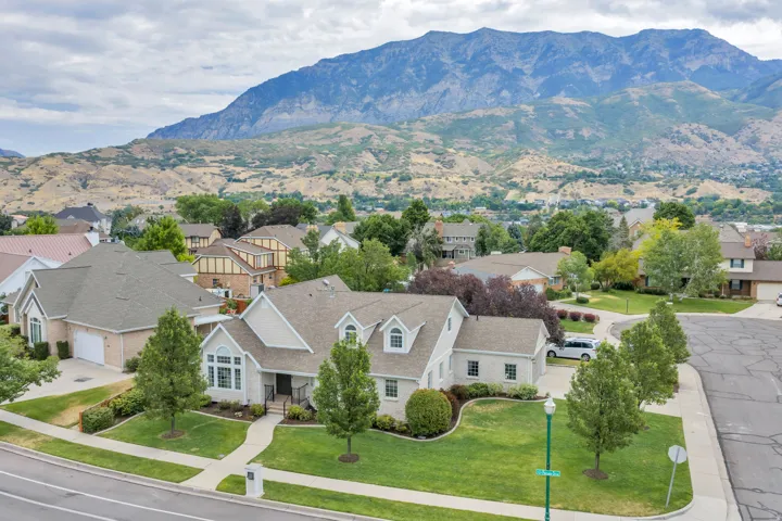 Traditional-style residence featuring a prominent mountain backdrop, lush green landscaping, and mature trees