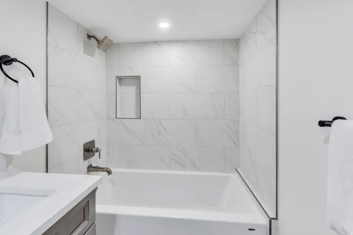 Bathroom featuring a full-size bathtub, white subway tile surround, built-in shower niche, recessed lighting, and brushed nickel fixtures