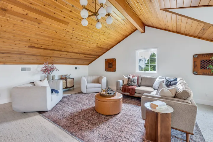 Vaulted wood-plank ceiling with exposed beams, illuminated by a multi-bulb chandelier