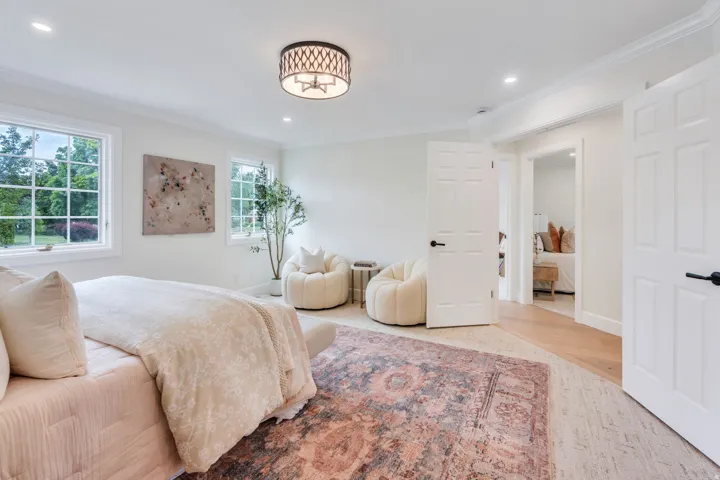 Bright interior space featuring multiple windows with grid patterns, a drum pendant light fixture, recessed ceiling lighting, crown molding, and two paneled doors with black hardware