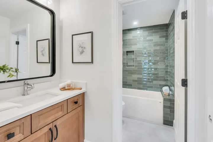 Bathroom vanity with a white rectangular undermount sink, chrome faucet, and wood-finish cabinetry featuring black hardware