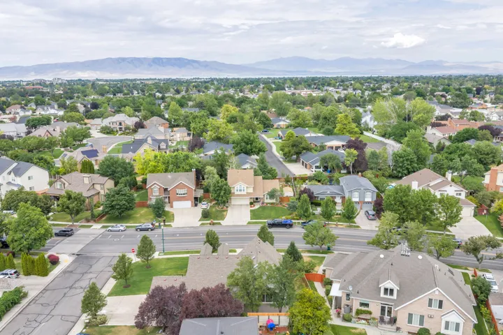 Expansive neighborhood featuring numerous residential properties with mature trees, paved streets, and mountainous terrain in the distance