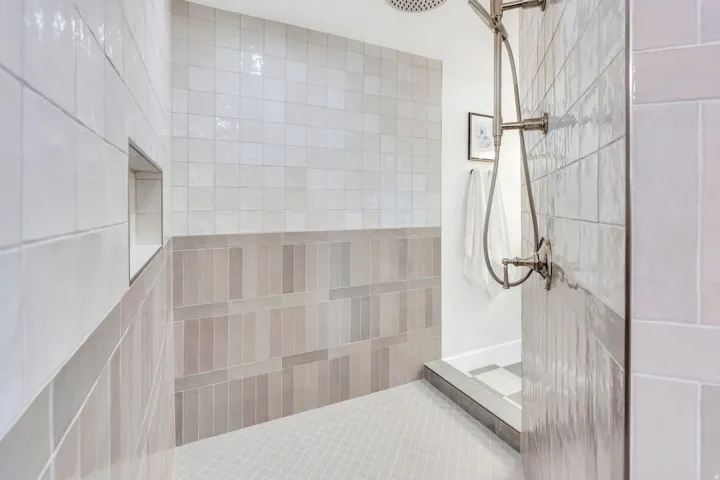 Walk-in shower with a rainfall showerhead, handheld shower fixture, recessed tile niche, and a combination of square and rectangular wall tiles