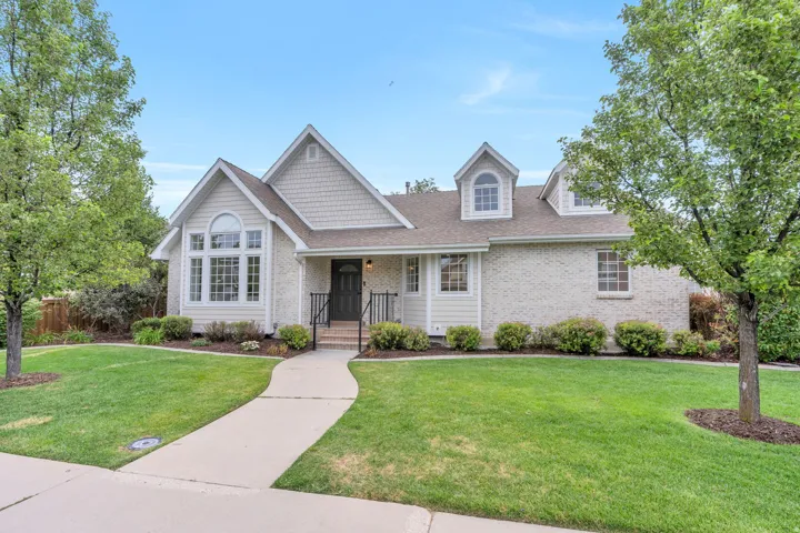 Light-colored brick exterior with shaker siding accents and a contrasting dark entry door