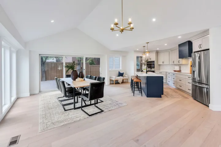 Spacious open-concept living area featuring a vaulted ceiling and light wood-finish flooring