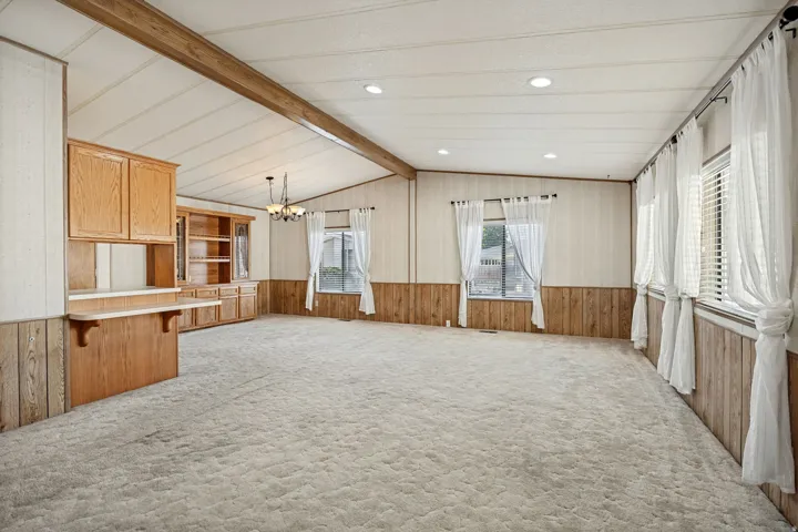 Vaulted ceiling with exposed beam, recessed lighting, built-in cabinetry, and wood-finish wainscoting