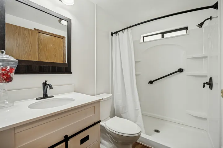 Bathroom featuring a single vanity with an integrated sink, white countertop, and dark-framed mirror