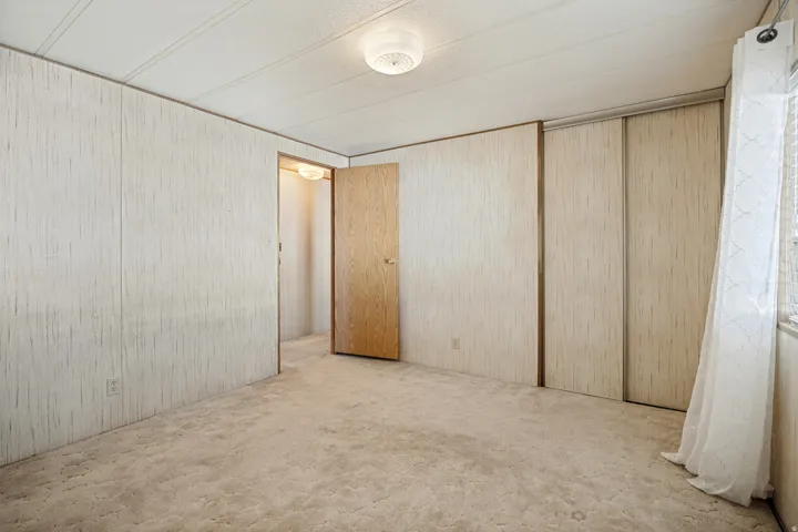 Carpeted room featuring patterned wall panels and a ceiling-mounted light fixture