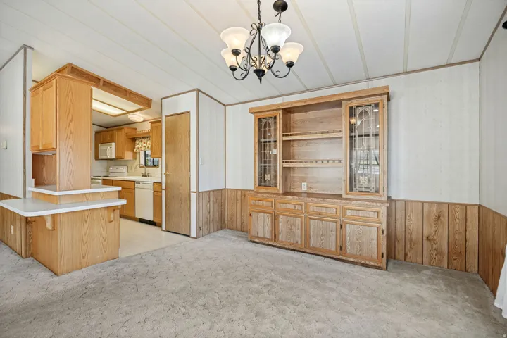 Integrated living space featuring a built-in wooden hutch with glass-front cabinetry, a breakfast bar, and wood-finish cabinetry in the kitchen