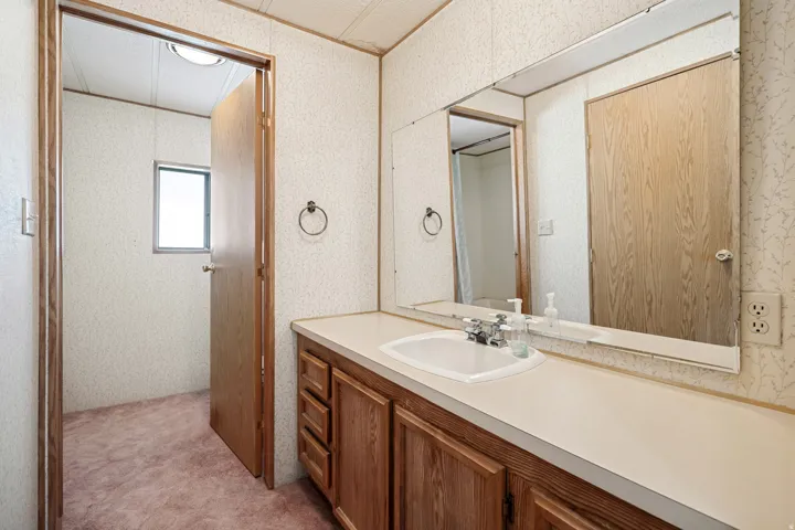Bathroom vanity with a white countertop and an integrated sink, featuring wood-finish cabinetry below