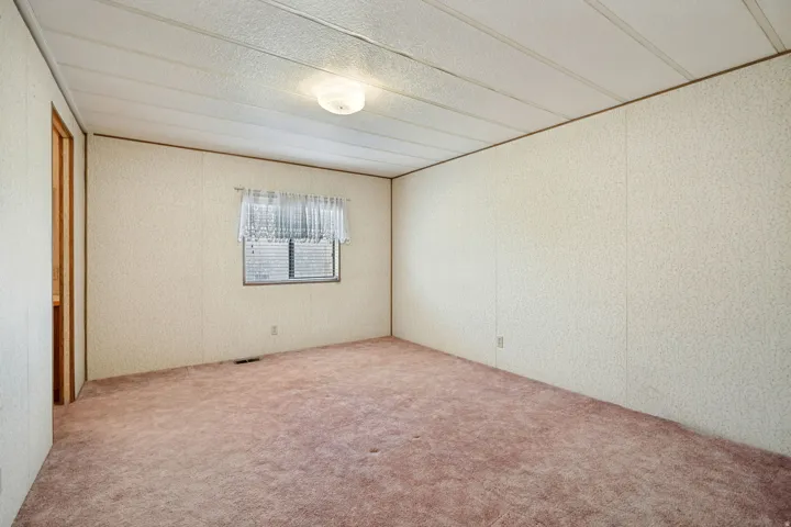 Interior room featuring a window with horizontal blinds, textured wall panels, and a flush mount ceiling light fixture