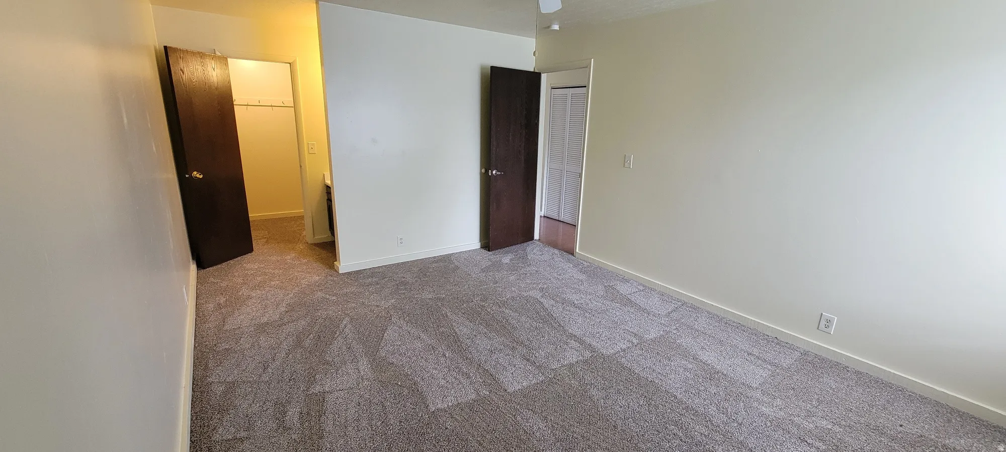 Spacious room with patterned carpeting and light-toned wall finishes