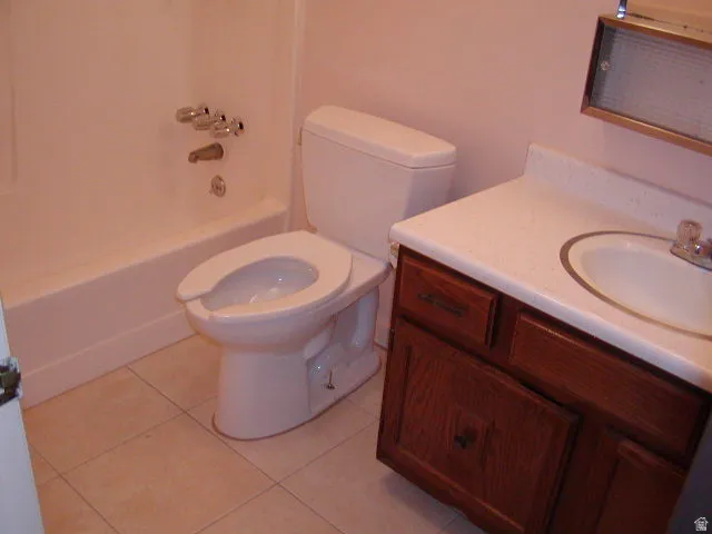 Bathroom featuring a white bathtub, toilet, and vanity with a white countertop and wood-finish cabinetry