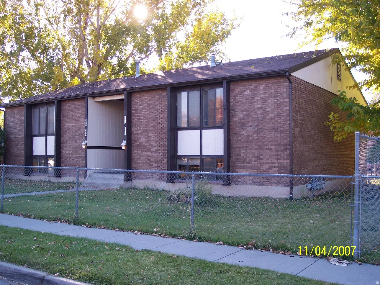 Brick exterior with brown trim and a dark shingle roof