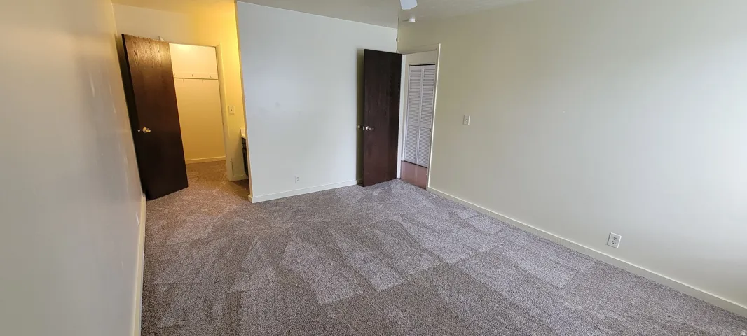 Spacious room with patterned carpeting and light-toned wall finishes