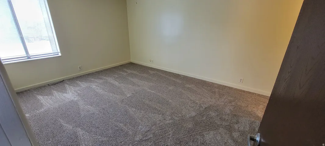 Spacious room featuring neutral carpeting and light-toned walls