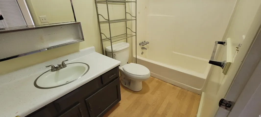 Bathroom featuring a built-in vanity with an integrated sink, a white countertop, a mirrored medicine cabinet, and a white bathtub