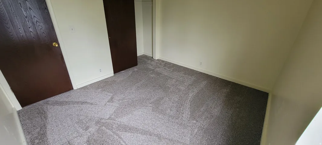 Room featuring neutral-toned walls, grey carpeting, and dark wood-finish doors