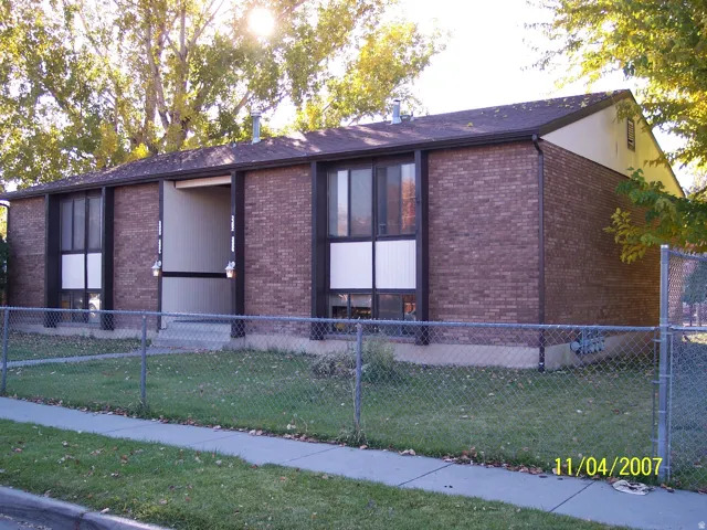 Brick exterior with brown trim and a dark shingle roof