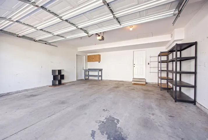 Spacious garage featuring a concrete floor, overhead door, built-in cabinetry, and two internal access doors