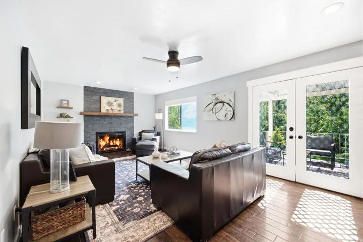 Living area featuring wood-finish flooring and a stone-clad fireplace with a wood mantel
