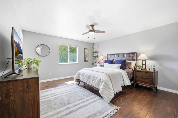 Spacious room featuring wood-finish flooring, a window offering natural light, and a ceiling fan