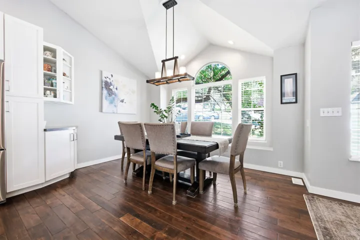 Dining area featuring vaulted ceilings, wood-finish flooring, and a contemporary chandelier