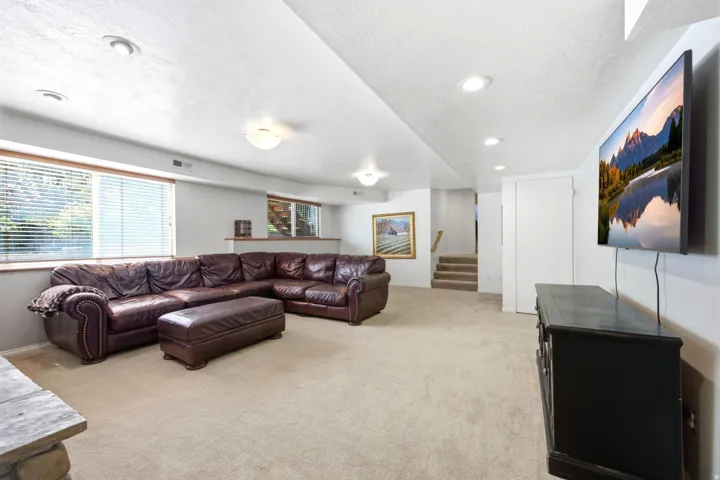 Spacious lower-level room featuring recessed lighting, light-colored carpeting, multiple windows with blinds, and white painted walls