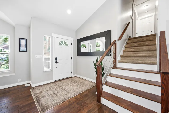 Entryway featuring wood-finish flooring, a white paneled door with a transom window, and dual vertical windows with blinds