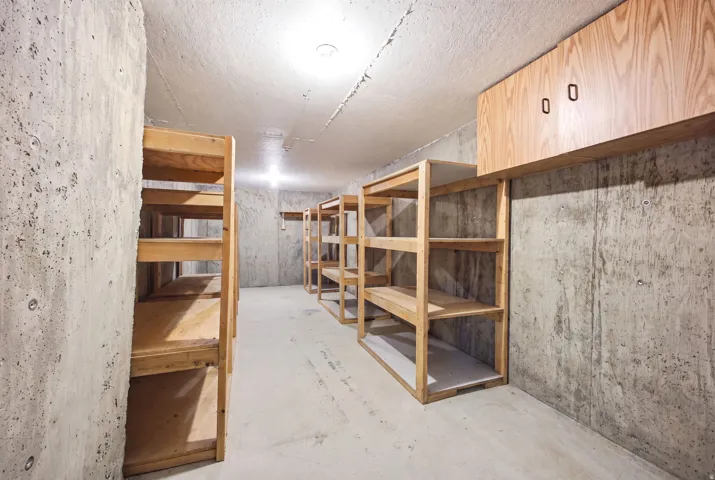 Concrete walls and flooring in a dedicated storage area, featuring multiple rows of built-in wooden shelving units