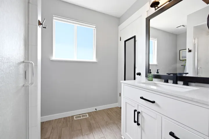Bathroom featuring a white vanity with quartz countertop, under-mount sink, and matte black fixtures