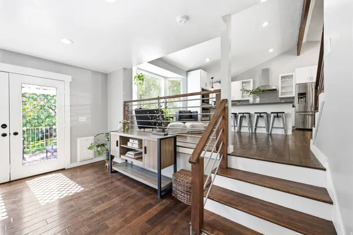 Multi-level interior featuring wood-finish flooring, white walls, and a contemporary kitchen