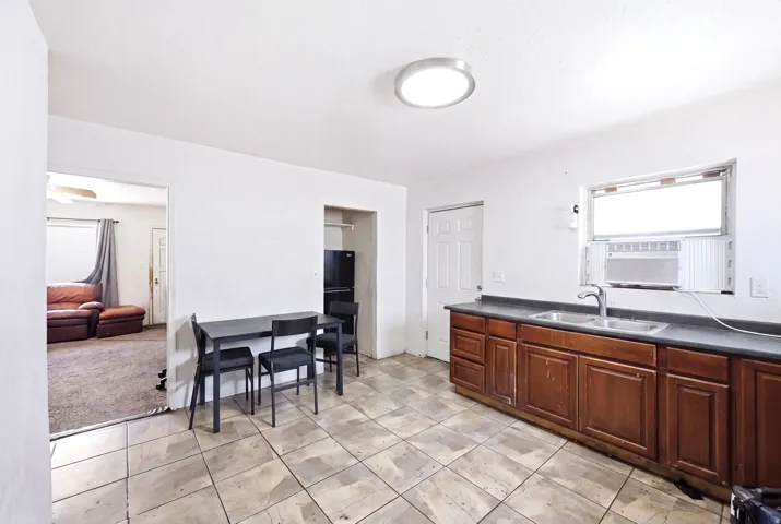 Kitchen area featuring tile flooring, wooden cabinetry with a dark countertop, and a double basin sink with a chrome faucet