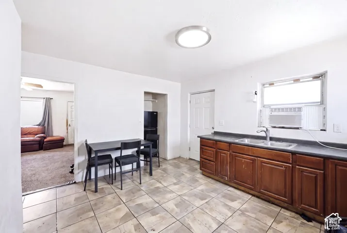 Kitchen area featuring tile flooring, wooden cabinetry with a dark countertop, and a double basin sink with a chrome faucet