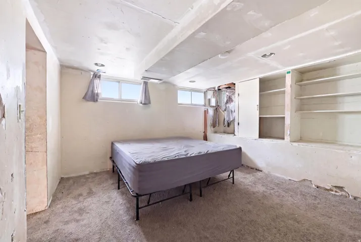 Carpeted room featuring recessed lighting, built-in shelving, two windows, and a built-in storage cabinet