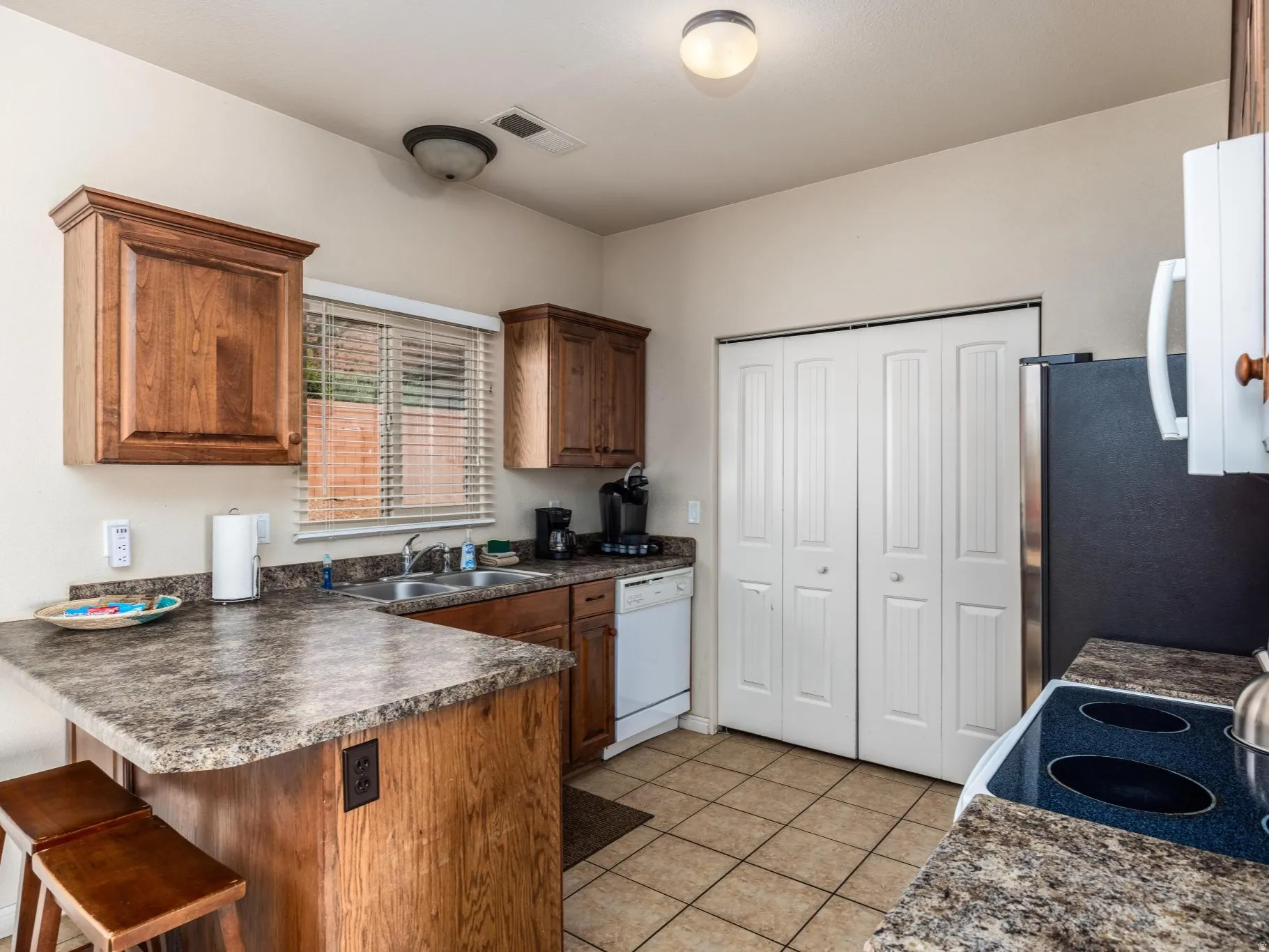 Kitchen featuring wood cabinetry, stone-look countertops, and tile flooring