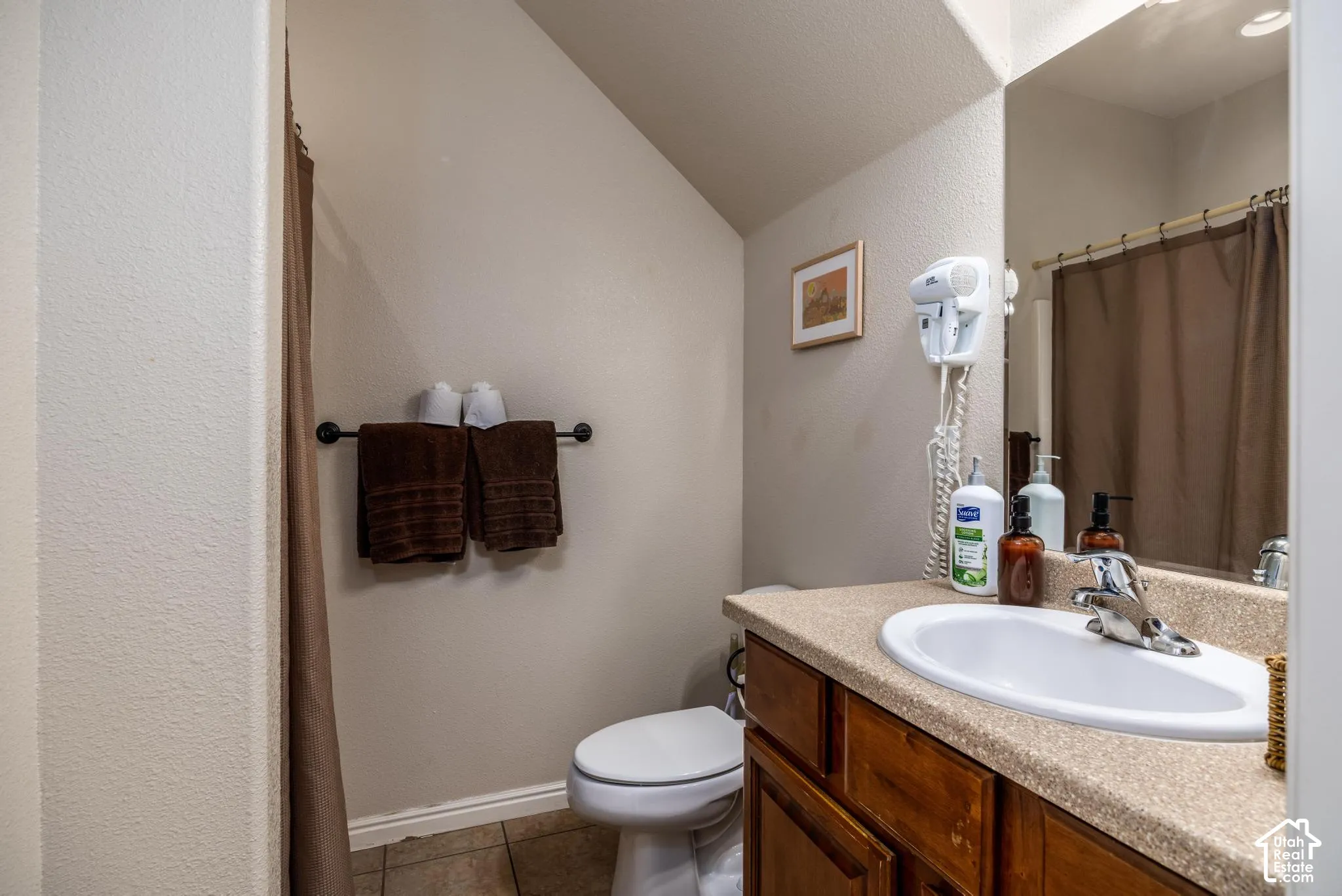 Bathroom featuring a white oval sink, wood-finish vanity with cabinet storage, a speckled countertop, and a large wall-mounted mirror