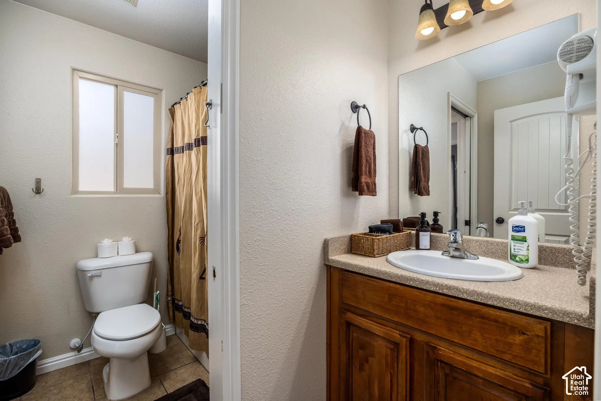 Bathroom featuring a wood-finish vanity with a built-in sink, a light-toned countertop, and a wall mirror