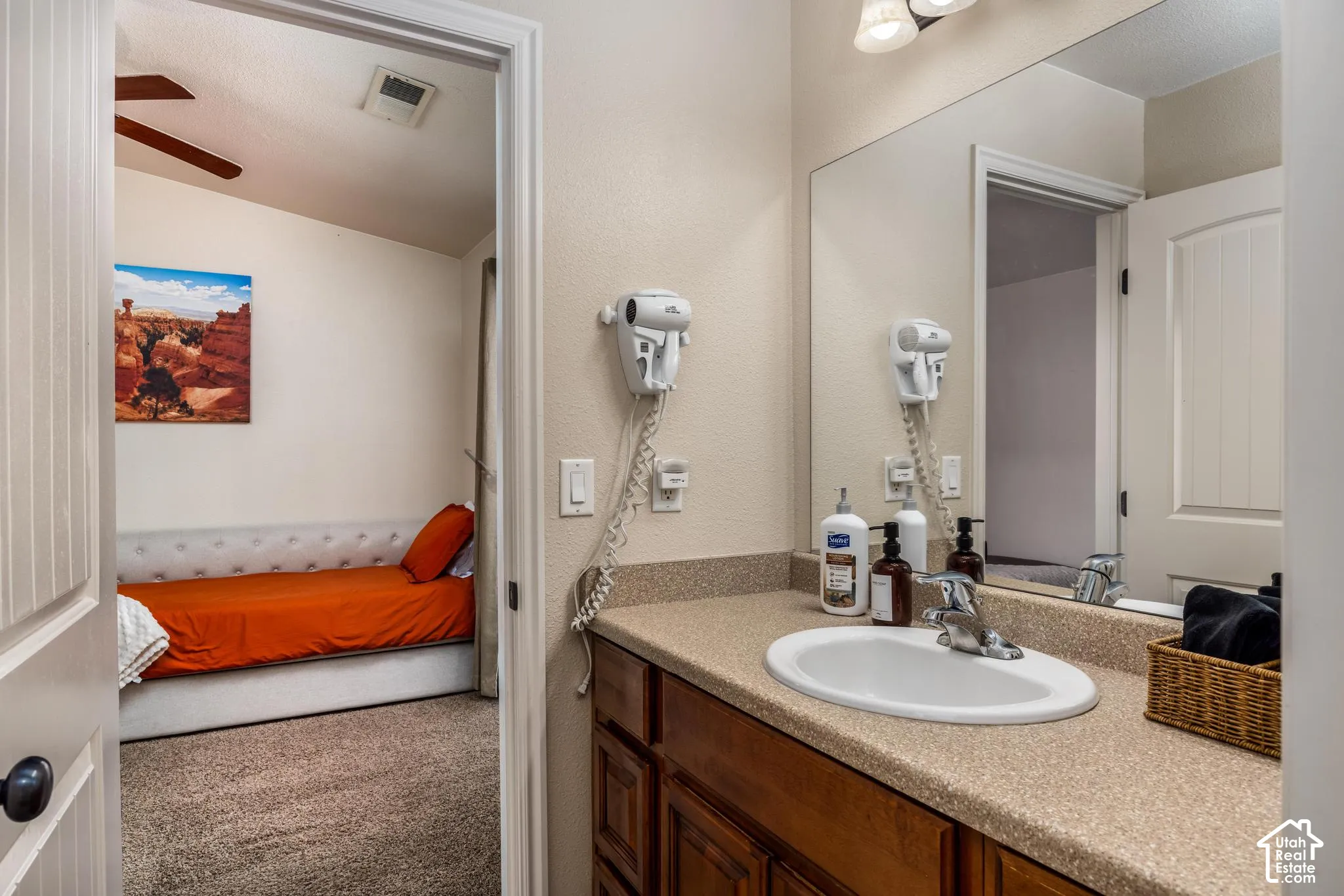 Bathroom vanity featuring an oval sink, speckled countertop, and wood-finish cabinetry
