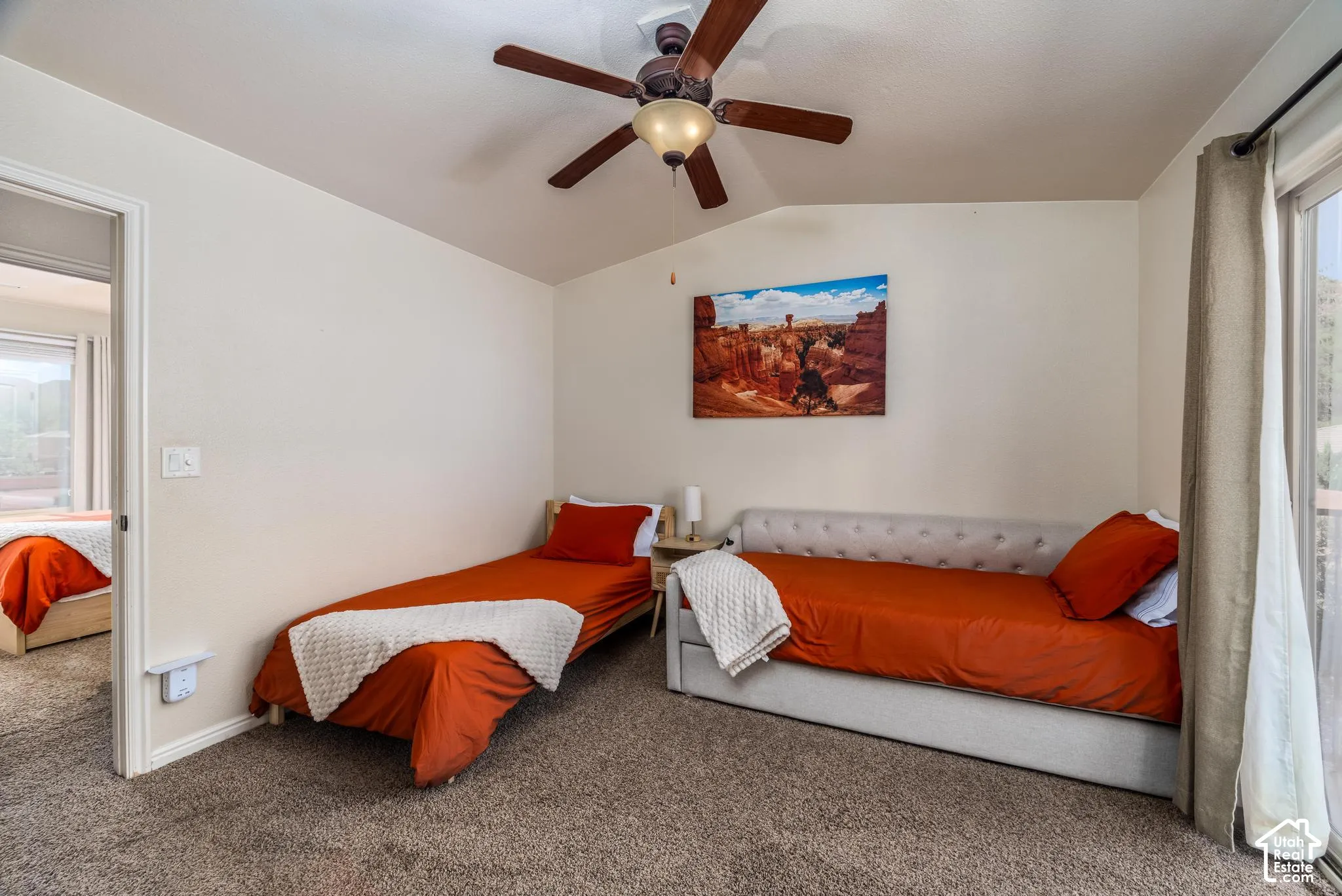 Carpeted room featuring a ceiling fan with integrated lighting, a sliding glass door, and a painted interior wall