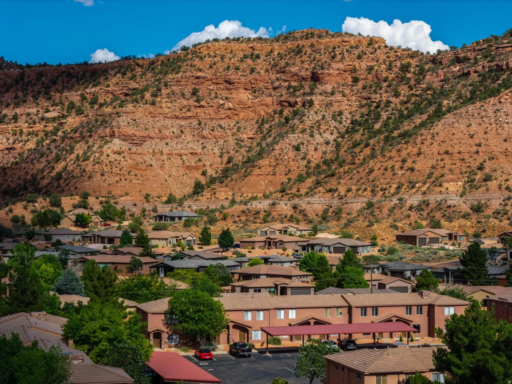 Community nestled against a dramatic red rock mountainside