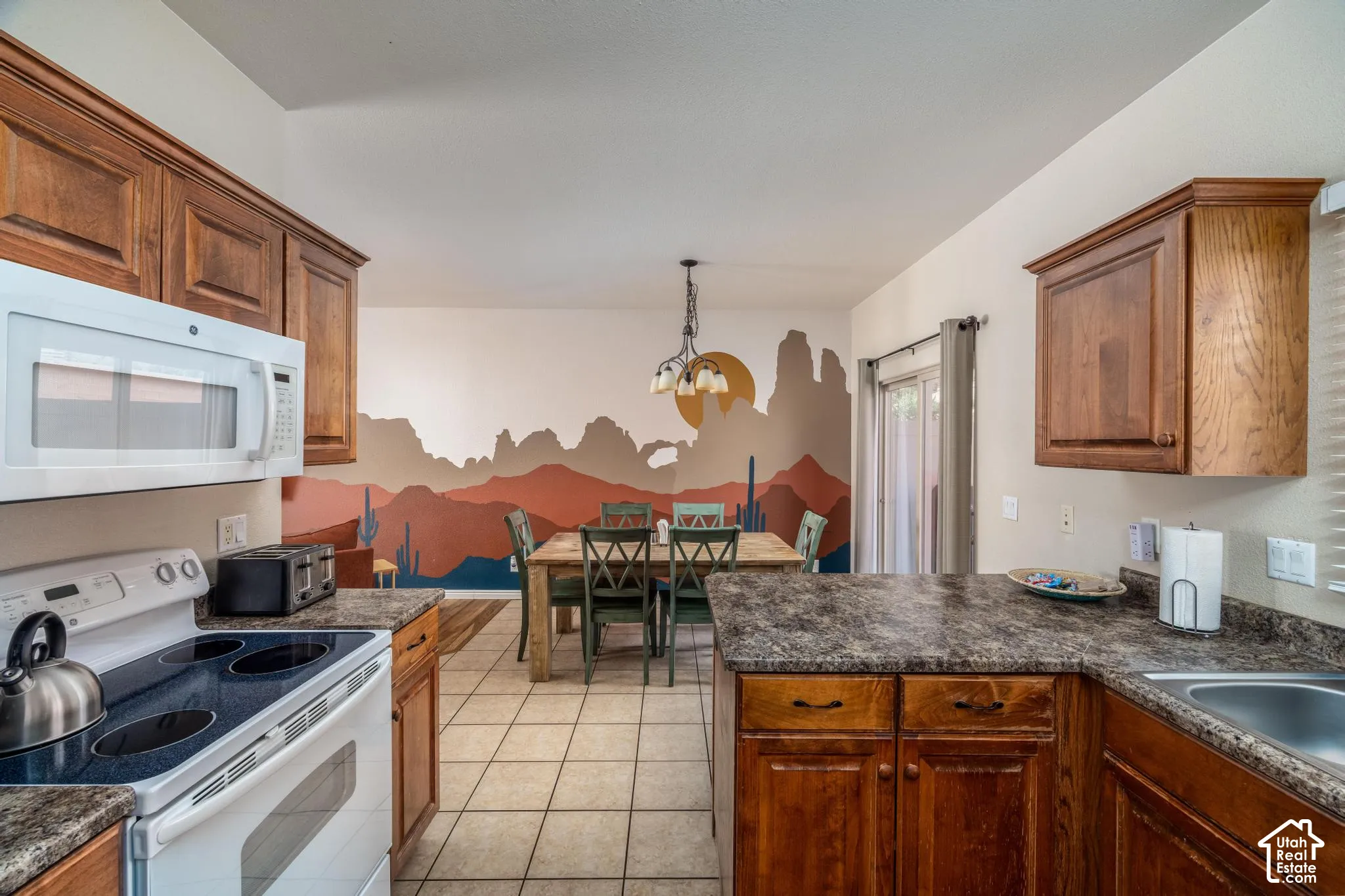 Kitchen featuring wood cabinetry, white appliances, and speckled countertops