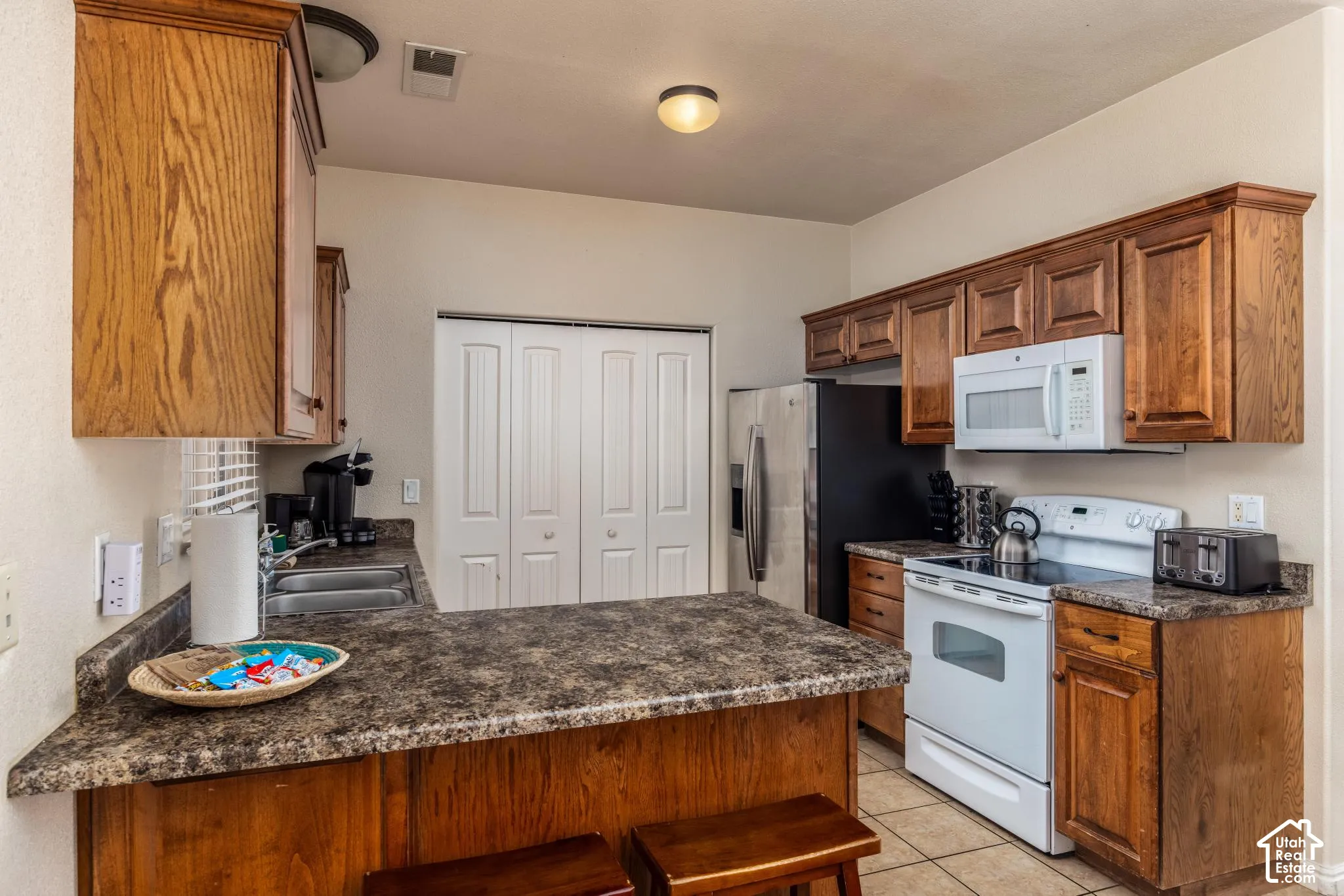 Kitchen featuring wood-finish cabinetry, speckled countertops, and tile flooring