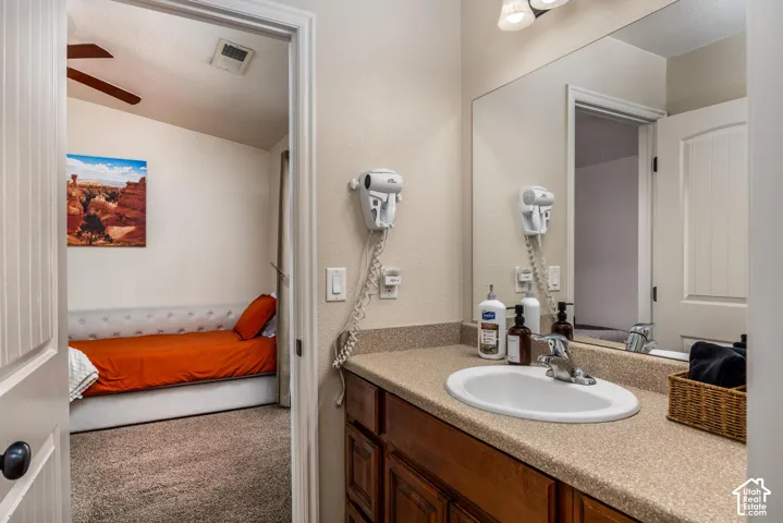 Bathroom vanity featuring an oval sink, speckled countertop, and wood-finish cabinetry